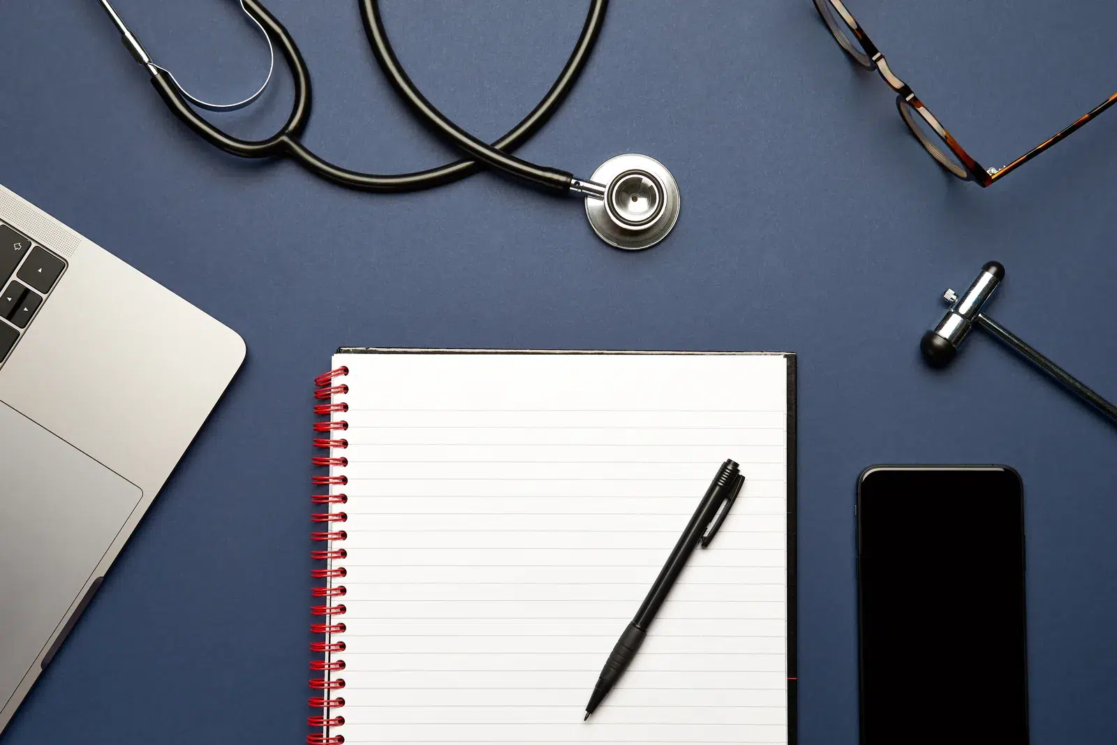 Fonendoscopio, cuaderno de notas y teléfono sobre la mesa de consulta